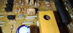 Zbliżenie na płytkę elektroniczną z widocznymi elementami elektronicznymi i oznaczeniami.