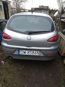Srebrny samochód stoi zaparkowany na podwórku, widziany od tyłu.