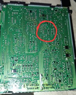 Spód zielonej płytki PCB z czerwonym okręgiem zaznaczającym fragment ścieżek i lutów