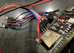 ESP32 with connected colorful wires on a black surface.