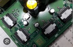 Zbliżenie na płytkę drukowaną z kilkoma układami scalonymi i kondensatorami.