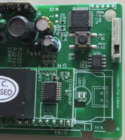 Image of a printed circuit board with visible electronic components, including two microcontrollers, capacitors, and a button.