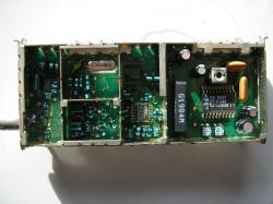 Zdjęcie wnętrza układu radiowego z różnymi komponentami elektronicznymi, w tym cewkami i układem scalonym.