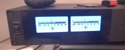 Device front panel with two blue-backlit VU meters and a side rocker power switch