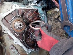 Osoba trzymająca pierścień dystansowy przed mechanizmem maszyny.