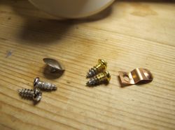 Screws and Brass Bracket on Wood Metal screws and a brass bracket on a wooden surface.