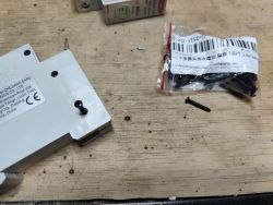 Electrical component and screws on workbench Close-up of electrical component with screws and screw pack on wooden surface