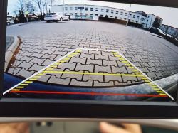 Widok z kamery cofania samochodu na parkingu.