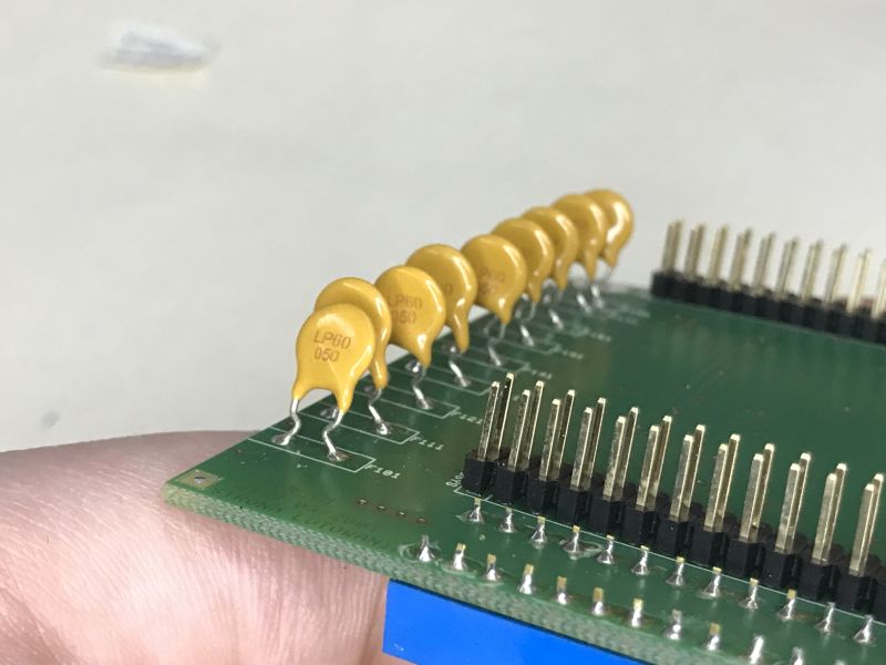 Close-up of LP60-050 yellow polymer fuses on a green PCB with gold pin headers