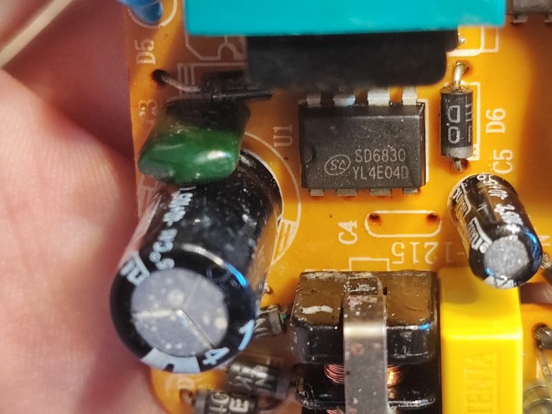 Wnętrze zasilacza z widocznym uszkodzonym kondensatorem