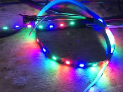 Colorful LED Strip on Wooden Surface LED strip with multiple colorful lights on a wooden surface.