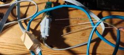 Close-up of a makeshift cable: a USB-DB9 cable connected to wires ending in sewing needles.
