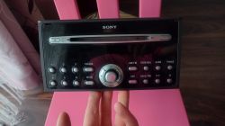 Radio samochodowe marki Sony trzymane na dłoni, widoczny panel z przyciskami i pokrętłem.