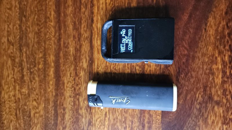 Małe czarne urządzenie prototypowe z ekranem OLED obok zapalniczki Spark