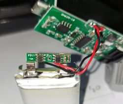 Zbliżenie na akumulator litowo-polimerowy z podłączonym przewodem i płytką elektroniki.