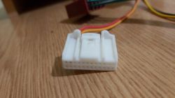 Weißer Plastikadapter für Autoradio mit Kabeln.