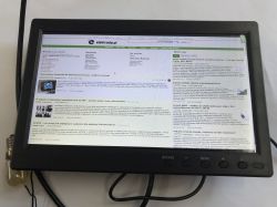 Small black monitor on a desk showing elektroda.pl, with control buttons along the bottom bezel