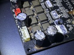 Zdjęcie uszkodzonej płytki PCB wzmacniacza z wylanymi kondensatorami elektrolitycznymi.