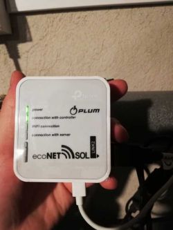 Person holding a PLUM ecoNET SOL router with visible LED indicators.