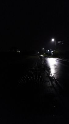 Ulica nocą oświetlona latarniami LED, mokra nawierzchnia odbija światło