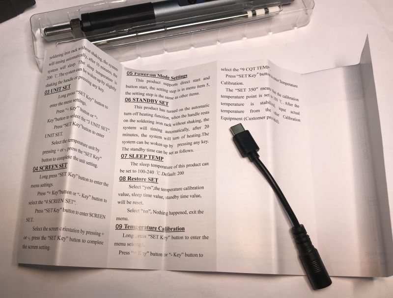 Lutownica, instrukcja i przejściówka Jack na USB-C leżące na białym tle.