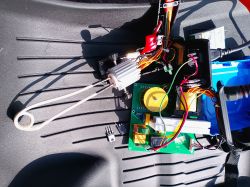 Disassembled device with PCB, wires, heatsink, and white coiled heating element on a black textured surface