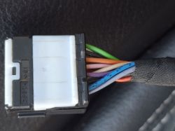 Zbliżenie na białą wtyczkę elektryczną z wiązką kolorowych przewodów w oplocie