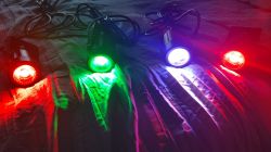 Four spotlights emitting different colors: red, green, blue, and white, placed on a dark background.
