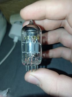 Zbliżenie na lampę elektronową trzymaną w ręce, widoczne piny i elementy wewnętrzne