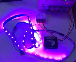 Purple-lit LED strip on a table connected by wires to an LED controller module
