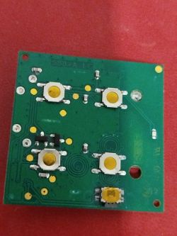 Płytka drukowana PCB z czterema przyciskami i żółtymi stykami na zielonym tle.