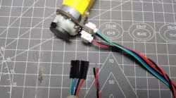 DC Motor with Encoder on Measurement Mat DC motor with encoder and colored wires on a measurement mat background.