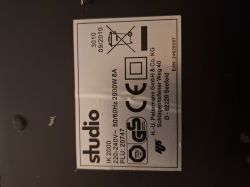 Etykieta techniczna na urządzeniu elektrycznym z logo „studio”, oznaczeniami CE i GS oraz informacjami o mocy i napięciu.