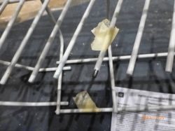 Fragment kosza zmywarki z fragmentami skorodowanej farby.