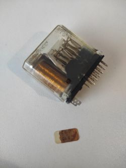 Przekaźnik o wymiarach około 35x35x23 mm z widocznymi stykami i częścią metalowej cewki.