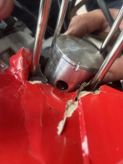 Zniszczony tłok silnika z metalowym bolcem zablokowanym między tłokiem a cylindrem.