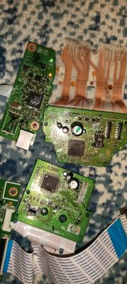 Trzy zielone płytki PCB i dwie taśmy elastyczne na niebieskim, wzorzystym tle