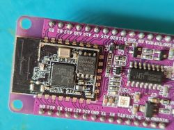 Close-up of a purple PCB with a Wi‑Fi module, CH340C chip, and soldered pin headers