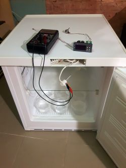 Otwarta zamrażarka z osprzętem elektronicznym na górnej pokrywie.