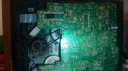 Wnętrze urządzenia elektronicznego z widoczną płytą główną i paskiem napędowym.
