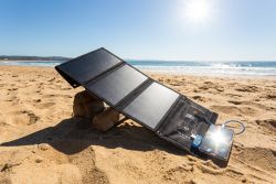 Solar panel on beach connected to device, lying in direct sunlight