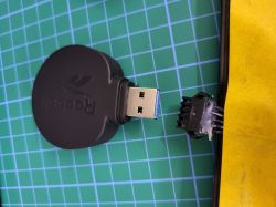 Adapter USB Reebok i przewody z końcówką 5-pinową na tle zielonej maty.