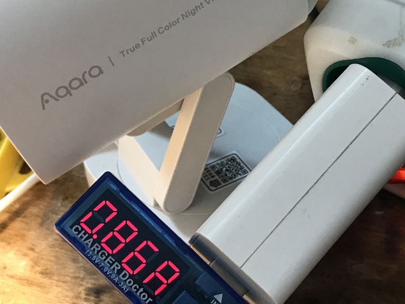 Kamera Aqara, watomierz Charger Doctor i biały adapter na drewnianym blacie