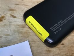 Czarny powerbank WPBBK1 z żółtą naklejką „CHARGE 2 HOURS BEFORE USE”.