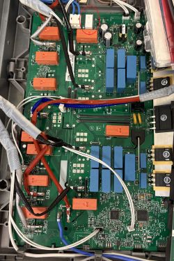 Inside a device: green PCB with relays and wires; a white component near the top is circled in red.