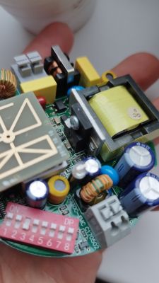 Zbliżenie na wewnętrzne elementy zasilacza, ukazujące różne komponenty elektroniczne na płytce drukowanej.