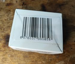 Box with Barcode on Wooden Table A box with a printed barcode lying on a wooden surface.