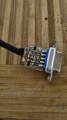 Zbliżenie na małą płytkę PCB z złączem RS232 i podłączonym kablem.