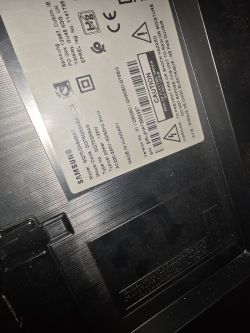 Etykieta identyfikacyjna na tylnej obudowie telewizora Samsung, z kodem modelu i ostrzeżeniami
