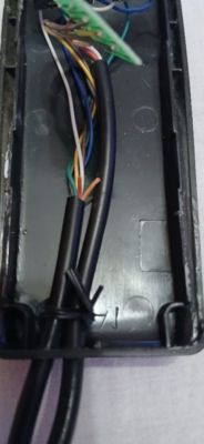 Zdjęcie wnętrza plastikowej obudowy z widocznymi kablami i przewodami.